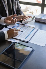 Wall Mural - Business team Two managers work on accounting documents and the team works together to give presentations and help solve problems with accounting documents. Close-up vertical image