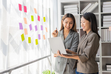 Wall Mural - Asian businesswoman is discussing a new business project on a tablet. In a meeting, two people discuss investment projects on data charts and planning strategies. About new business