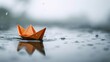 © LUPACO IMAGES - Orange Origami Boat Floating on Top of Body of Water