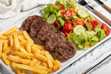 Wall Mural - Grilled meat balls. Grilled meatballs with salad and fries on a white background. Close up