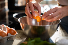 Woman Cracking An Egg Into A Bowl For Cooking At Home Kitchen