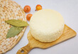 Round cut Adyghe cheese on a woven napkin on a white background