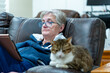 Senior woman reading a tablet sitting with her cat