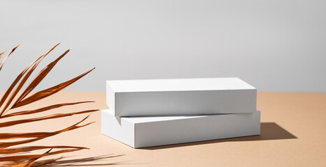 Wall Mural - Empty podium for product. Minimal two white boxes on a beige background with palm leaf.