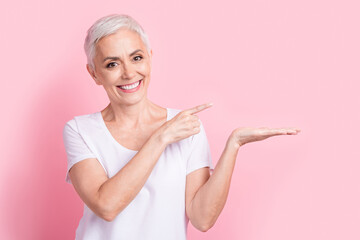 Wall Mural - Photo portrait of pretty retired female palm hold point empty space dressed stylish white outfit isolated on pink color background