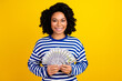 Photo of satisfied smart woman dressed striped pullover in glasses demonstrate bunch of dollars isolated on yellow color background