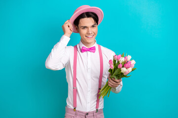 Canvas Print - Photo of good mood pleasant guy wear white shirt hold tulips touching pink headwear on romantic date isolated on blue color background