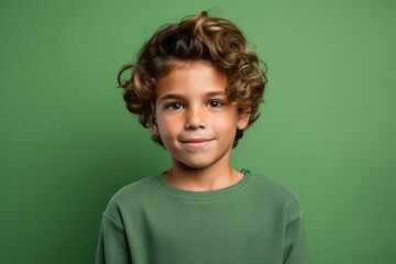 Portrait of a cute little boy with curly hair over green background