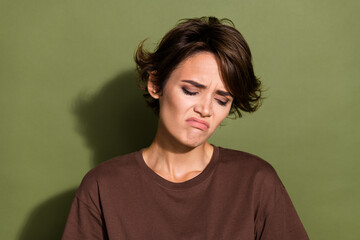 Wall Mural - Portrait of gloomy sad unhappy girl with short hairstyle wear oversize t-shirt look down crying isolated on green color background