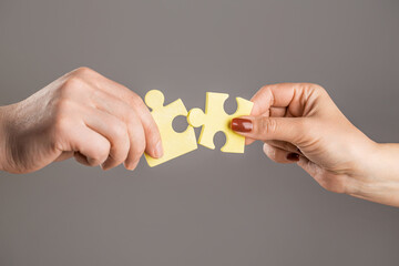 Wall Mural - Puzzles. Man and woman holds in hand a jigsaw puzzle. Business solutions, success and strategy concept. Hands connecting puzzle. Hand of the man and hand of woman fold puzzle, closeup