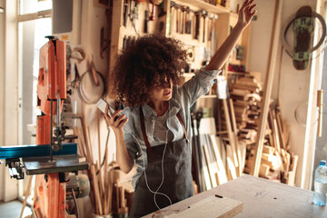 Craftswoman listening to music in woodshop