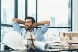 Fototapeta  - Portrait of relaxed young architect engineer resting and designing while sitting in modern home office. Male worker or manager take a break, holding hands behind head after finish project. Tracery