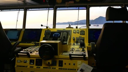 Modern and super functional navigational bridge of ultra large container ship, with steering wheel and radar and electronic charts equipment screens.