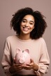 portrait of a happy mixed race young woman holding her piggy bank