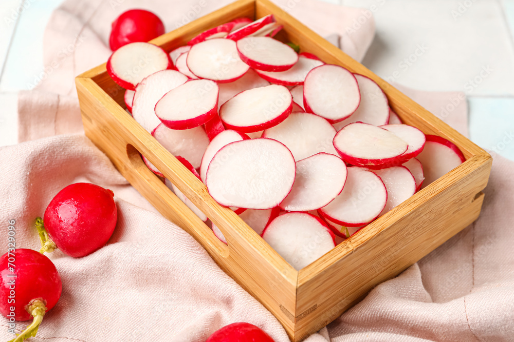 Fresh sliced radish in wooden box on light background