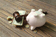 Piggy bank with judge gavel and money on brown wooden background. Concept of bankruptcy