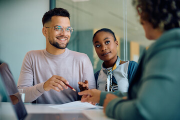 Young couple talking to their financial advisor before signing contract in office.