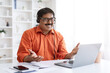 © Prostock-studio - Smiling mature indian man using laptop and headset