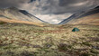 Camping in the moss with tent in Rondane national park with mountains, cloudy dramatic sky, Norway.