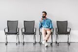 Fototapeta  - Pensive indian man in office with empty chairs, contemplating