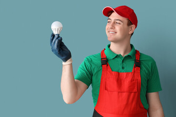 Poster - Male electrician with light bulb on blue background