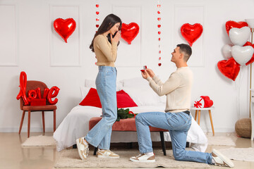 Poster - Young man proposing to his girlfriend in bedroom. Valentine's Day celebration