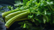  A Pile Of Celery Sitting On Top Of A Black Table Next To A Pile Of Green Leafy Vegetables On Top Of A Black Counter Top Of A Table.