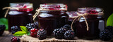 Fototapeta Panele - Fresh homemade blackberry jam in glass jar on a wooden background.Several fresh berries are near it
