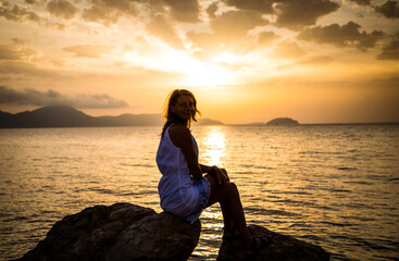 Wall Mural - woman enjoying sunrise by the sea