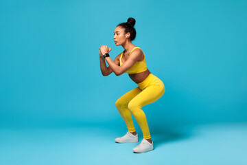 Wall Mural - Fit African American Lady Doing Deep Squat Exercise, Blue Background