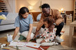 © Seventyfour - Full shot of smiling African American mother and father pointing at paper on floor and asking little daughter holding marker about her drawing