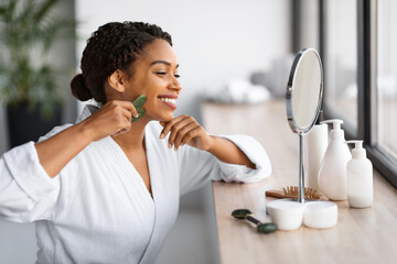 Wall Mural - Beauty Tools. Young Black Woman Making Face Massage With Gua Sha Scraper