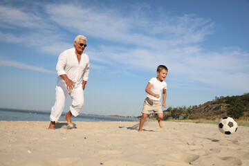 Canvas Print - Cute little boy and grandfather playing with soccer ball on sea beach