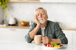 Tired elderly man resting his head on hand, falling asleep during breakfast