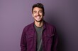 Portrait of a handsome young man smiling against a purple background.