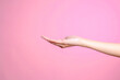 Hand showing palm up gesture isolated over pink pastel background, side view