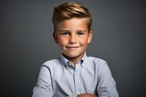 Portrait of a cute little boy in a blue shirt on a gray background