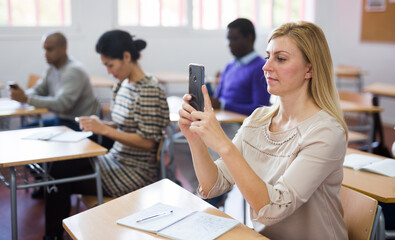 Wall Mural - Portrait of focused woman using mobile phone during adult education class