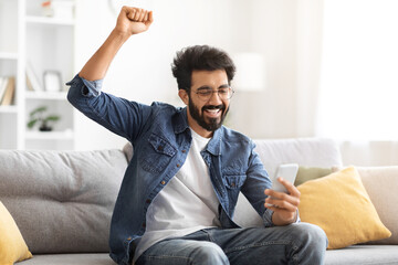 Sticker - Great News. Overjoyed Indian Man Looking At Smartphone Screen And Celebrating Success