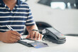 Young man using a credit card reader to sign a bill at the dealership's new automobile showroom.