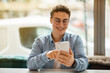 © Prostock-studio - Cheerful millennial european guy in glasses using mobile phone, chatting
