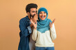 Delighted arab muslim couple sharing joyful secret, man whispering into woman's ear