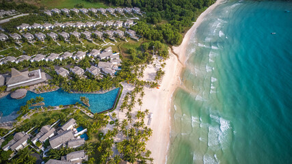 Wall Mural - Aerial view of a luxury beachfront resort with tropical palm trees and an inviting blue swimming pool, ideal for travel or vacation concepts