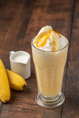 Wall Mural - Banana smoothie in glass cup on wooden table