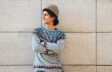 Wall Mural - urban young man wearing winter clothes and arms crossed posing on the wall