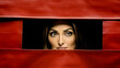 Playful Intrigue, A Radiant Woman Peeking Mischievously From Behind a Vibrant Red Curtain