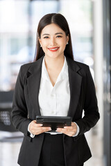 Wall Mural - Smiling confident business woman leader standing in office, holding digital tablet and looking at camera