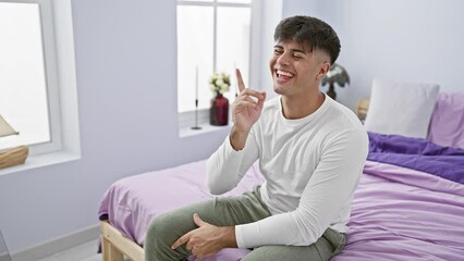 Canvas Print - Young hispanic man lying on bed wearing pyjama pointing finger up with successful idea. exited and happy. number one. at bedroom