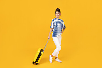 Wall Mural - A young girl with a yellow suitcase on a yellow background