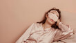 © ksu_ok - woman wearingbeage pyjamas jam sleep eye mask rest relax, isolated on studio background. Night nap concept